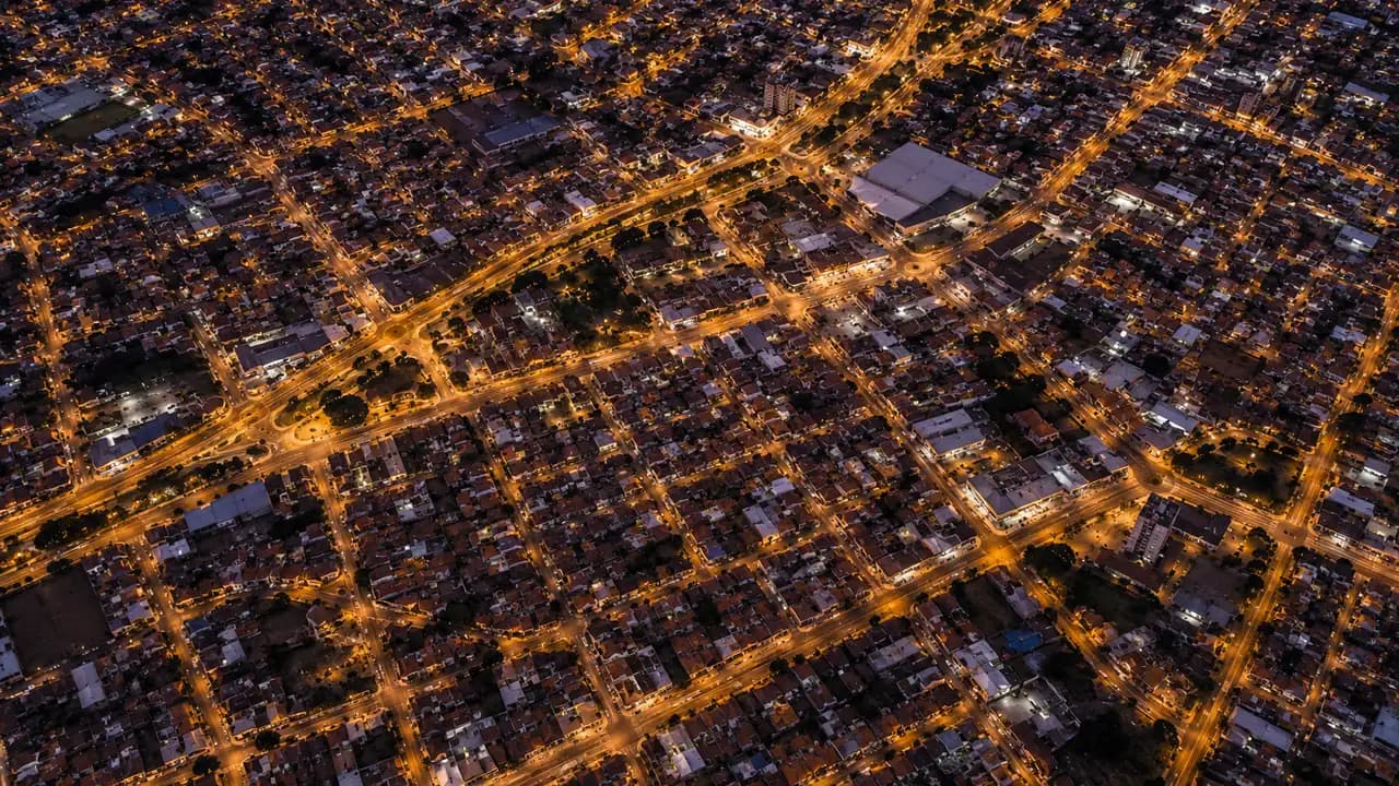 Vista aérea noturna de uma cidade do interior, com ruas iluminadas